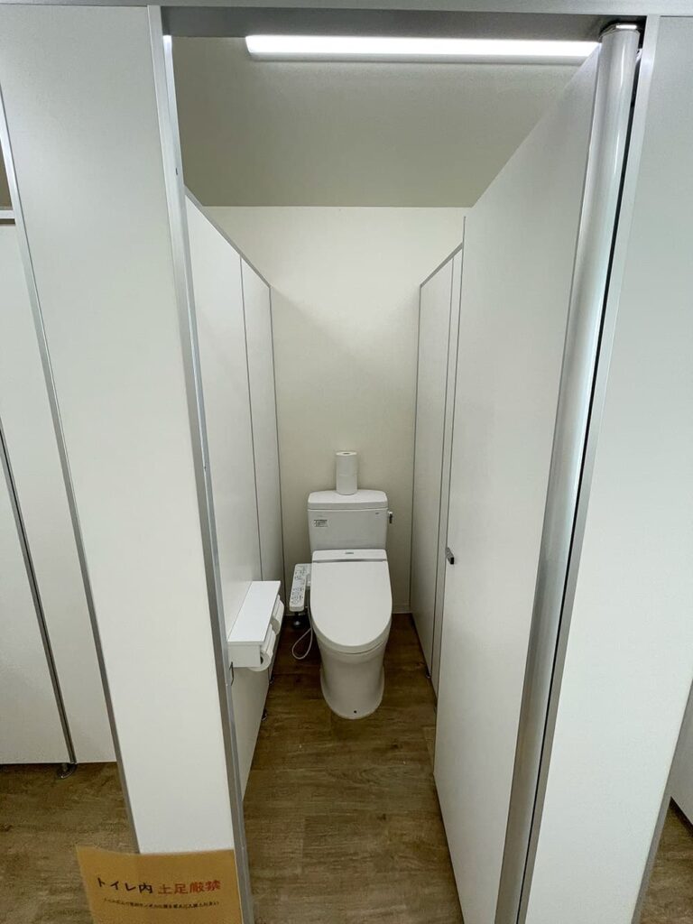 白いトイレブースの内部、最新のトイレと木目調のフローリング